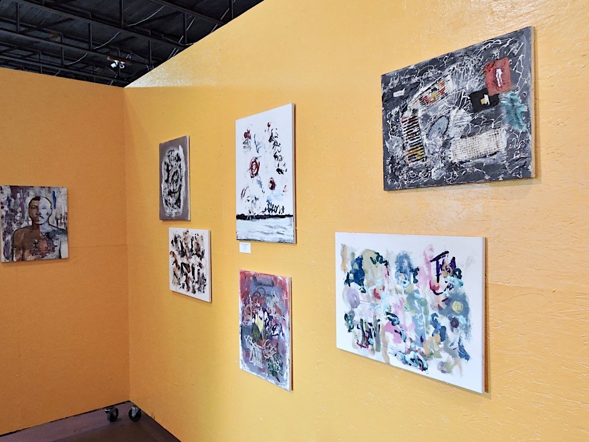 Abstract and contemporary artworks displayed on vibrant yellow walls at Studio 2500 art gallery.
